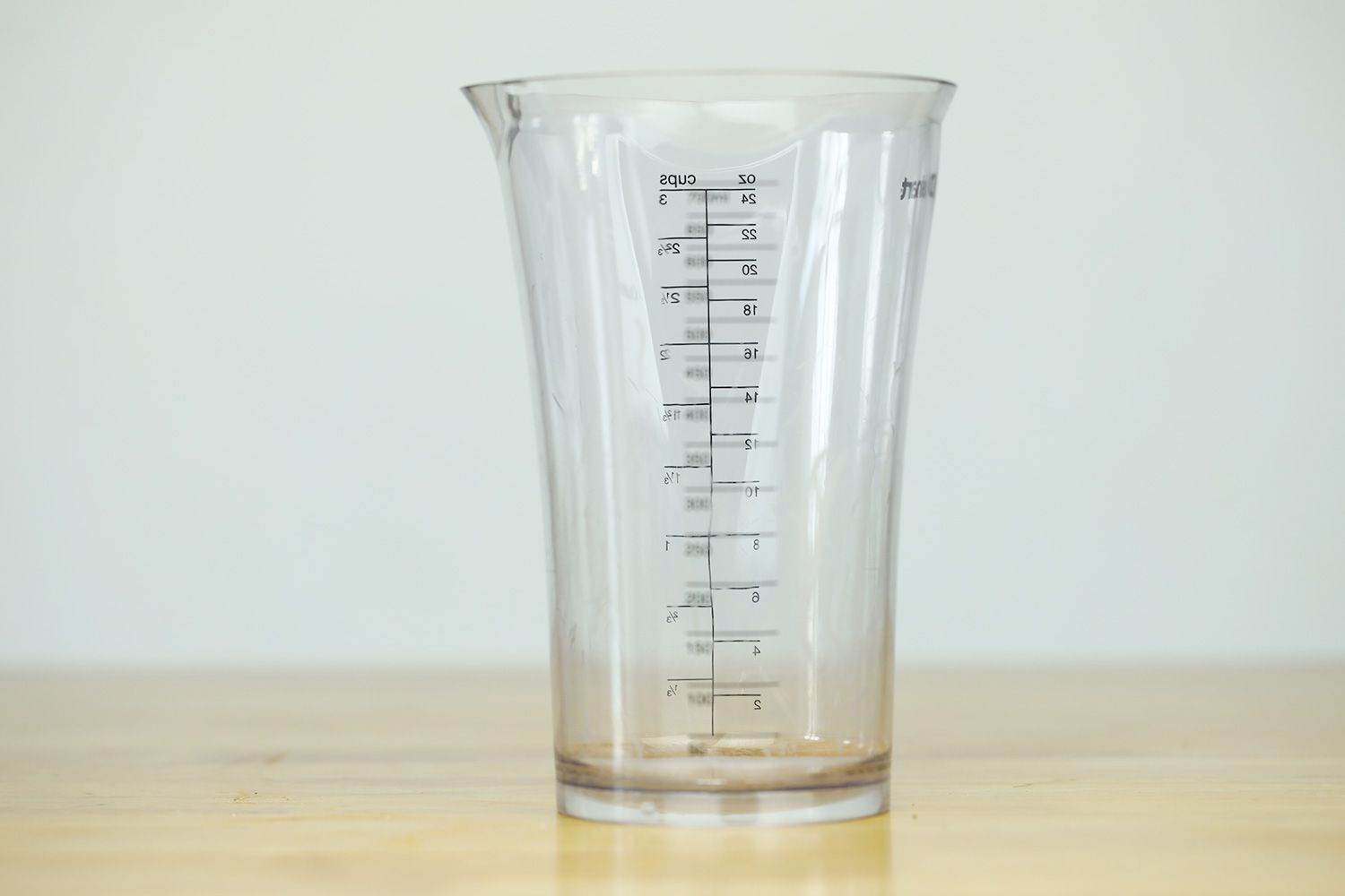 A 24-oz plastic beaker of the Cuisinart Smart stick standing on a yellow table.