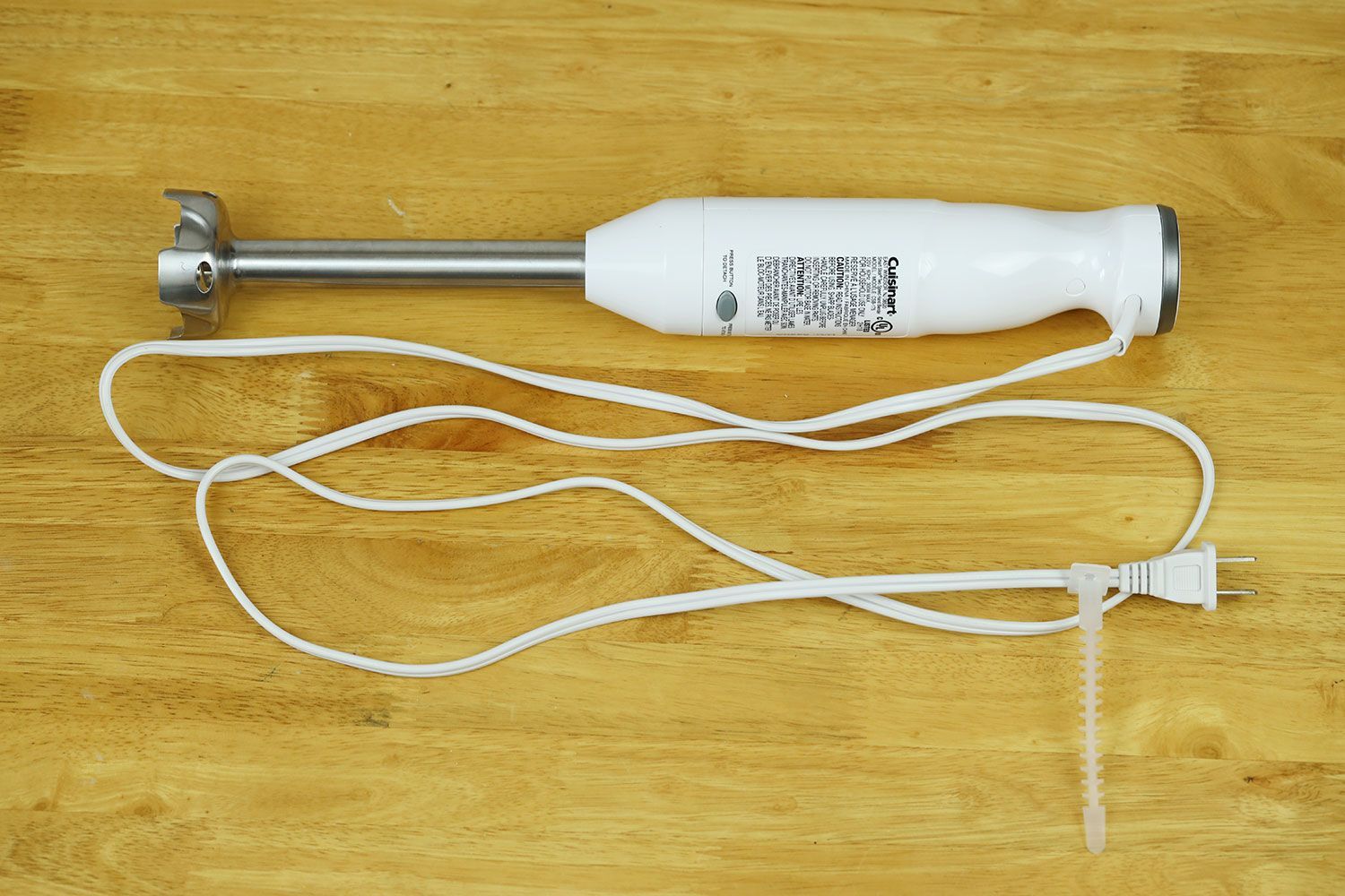 The Cuisinart Smart Stick Immersion Blender on a gray table with its power cord rolled up next to it.