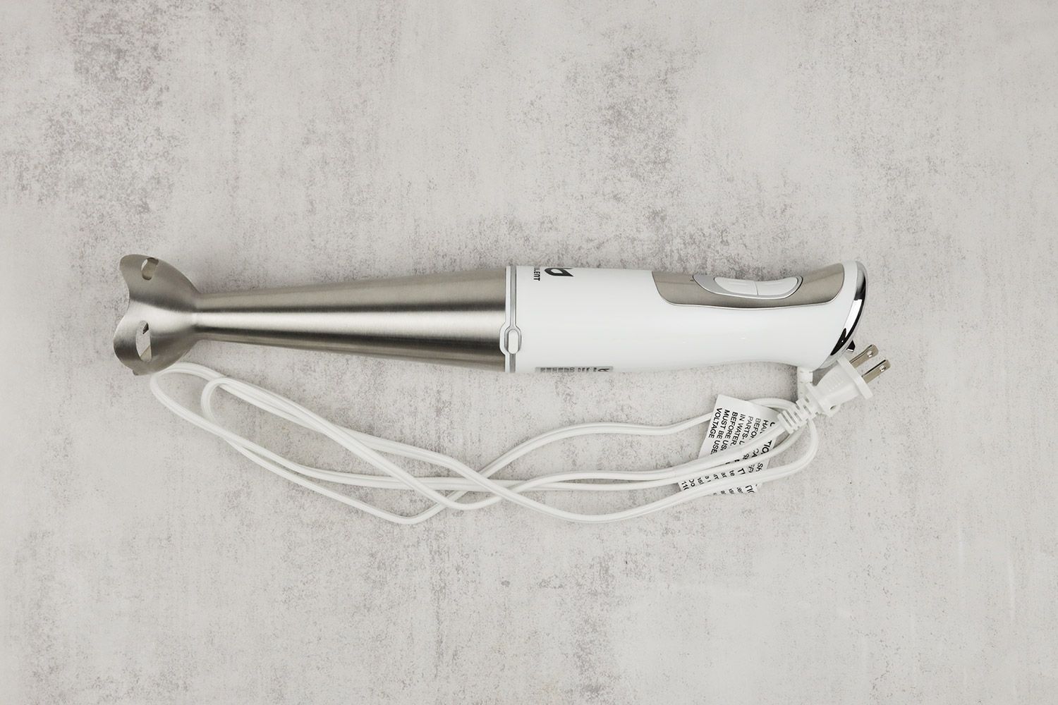 The UTALENT Immersion Blender on a gray table with its power cord that features a 2-prong plug rolled up next to it.