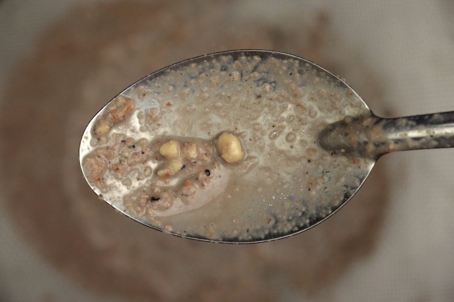 Using a spoon to remove a couple of almond chunks from the mesh strainer.