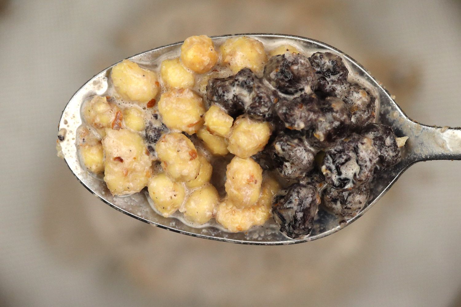 Scooping a spoon of solid chunks including dried blueberries and almonds that the Magic Bullet 11-Piece personal blender was unable to pulverize in the test of preparing protein shake from a stainless steel mesh strainer.