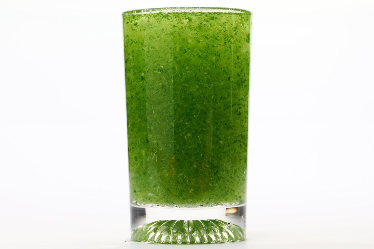 A glass of water with fibrous green pulp produced by the Magic Bullet personal blender.