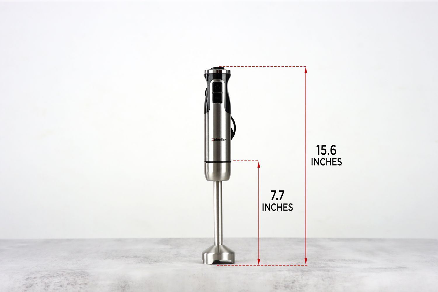 The Mueller Austria Ultra-Stick Immersion Blender standing on top of its blending shaft on a gray table, with the length of the blending shaft being noted to the side as 7.7 inches, and the total length of the unit as 15.55 inches.