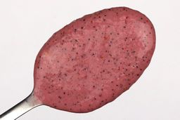 A spoon of fruity smoothie packed with blueberries, blackberries, strawberries, and mango made by the KOIOS Bullet Blender.