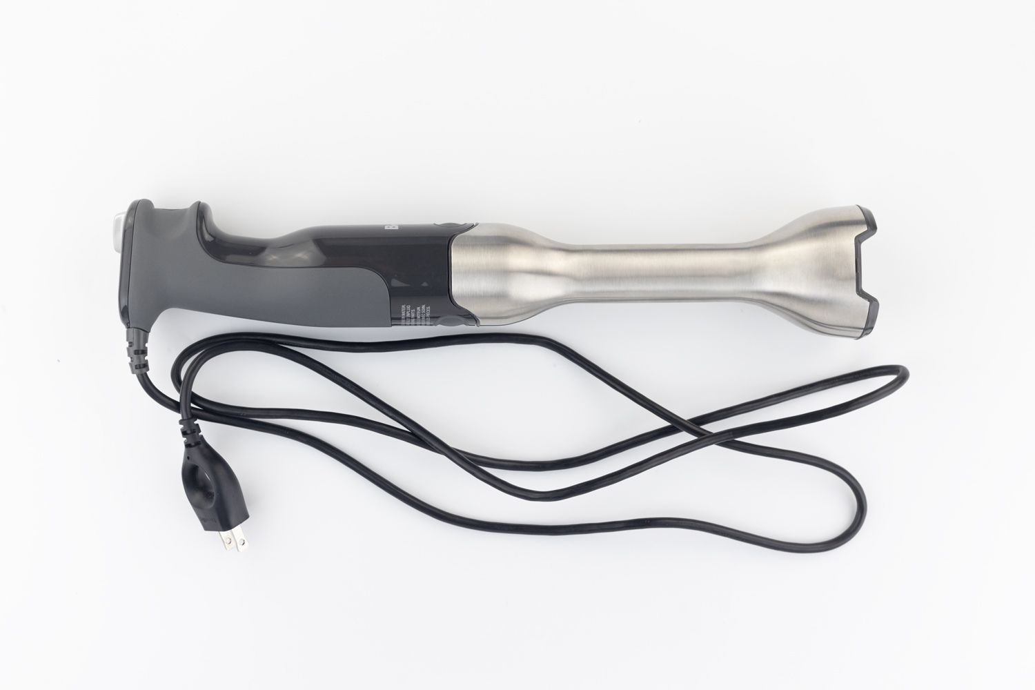 The Breville Immersion Blender on a white table with its power cord that features a 2-prong plug rolled up next to it.