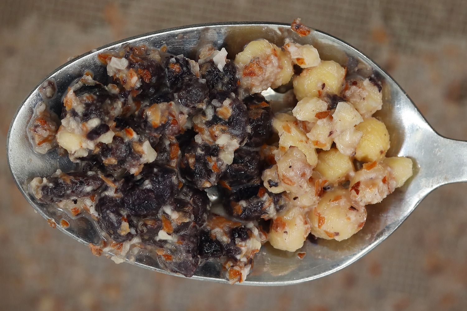 Scooping a spoon of solid chunks including dried blueberries and almonds that the Icucina personal blender was unable to pulverize in the test of preparing protein shake from a stainless steel mesh strainer. 