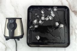 A black tray of crushed ice produced by the iCucina Single-Serve Blender being on a table.