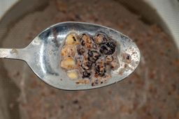 Using a spoon to scoop a small smattering of food chunks from a mesh strainer containing protein shake produced the BELLA personal blender.