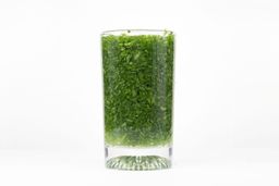 A glass of water with fibrous greens pulp produced by the BELLA Single-Serve Blender.