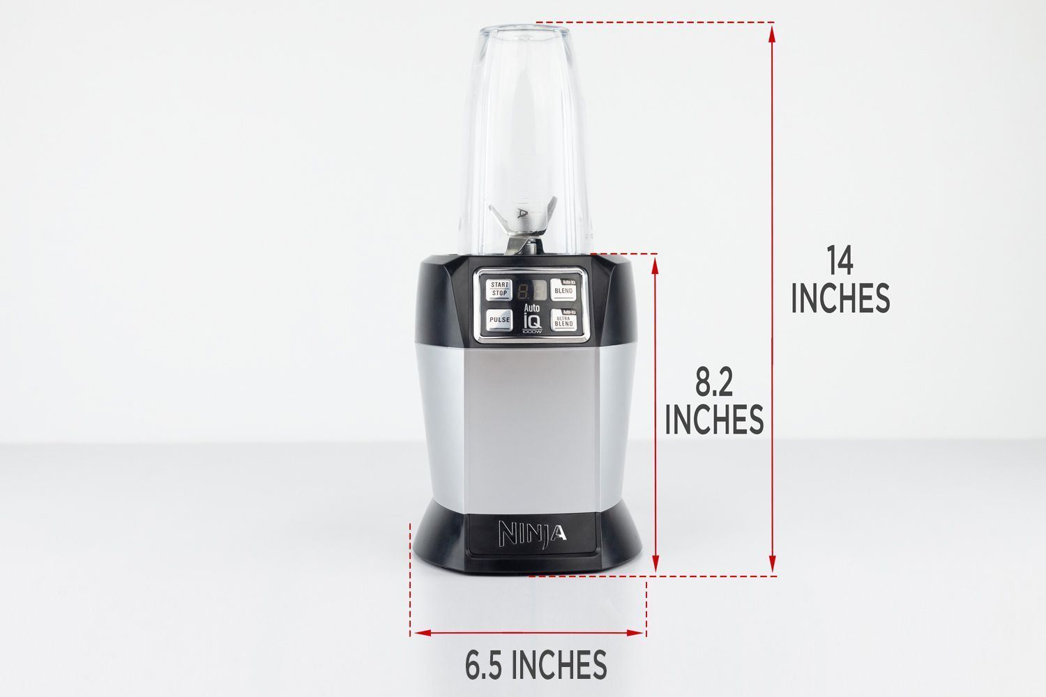 The Ninja Nutri 1000-watt personal blender standing on a gray table, with the length of its motor base being noted to the side as 8.2 inches, and the total length and width of the unit as 14 inches and 6.5 inches, respectively.