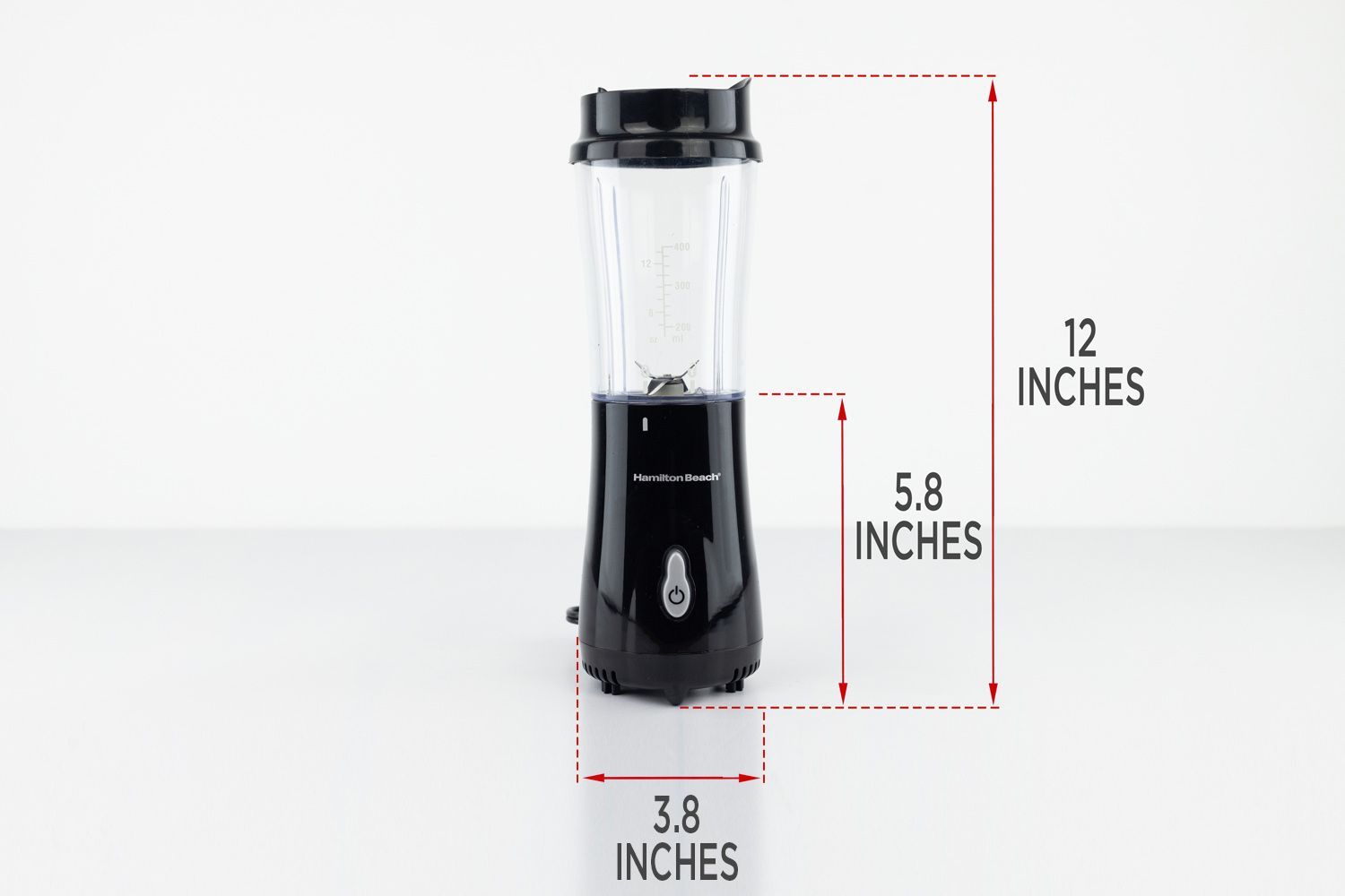 The Hamilton Beach 51101AV Personal Blender standing on a gray table, with the length of its motor base being noted to the side as 5.8 inches, and the total length and width of the unit as 12 inches and 3.8 inches, respectively. 