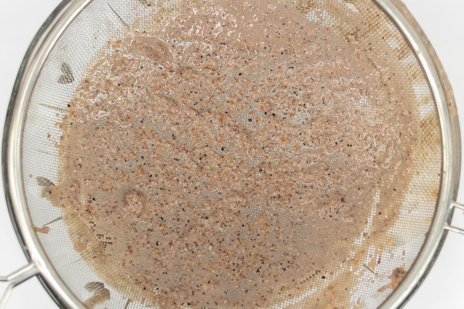 A batch of protein shake prepared by the Hamilton Beach is checked for smoothness by being drained through a stainless steel mesh strainer.