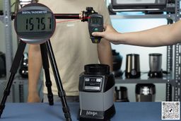 The Ninja AMZ493BRN motor base on a table with a hand pressing a digital tachometer on a tripod. Different blenders are in the background.