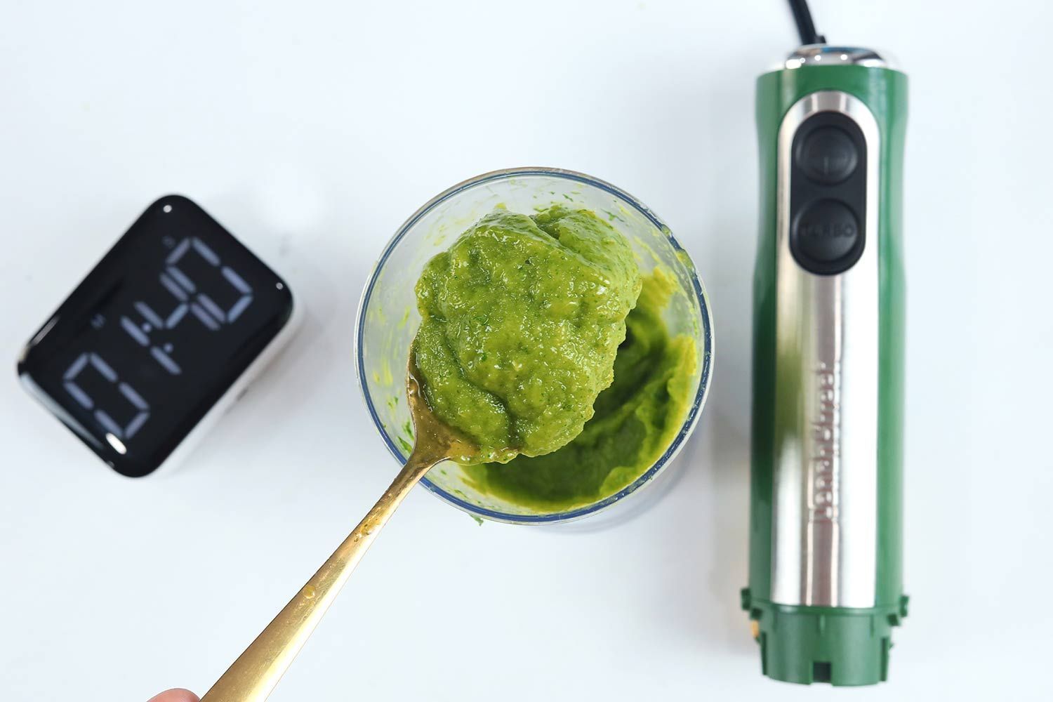 Scooping a spoon of smoothie from the plastic beaker to check its texture after the Peach Street Hand Blender had completed the test in 1:40 seconds.