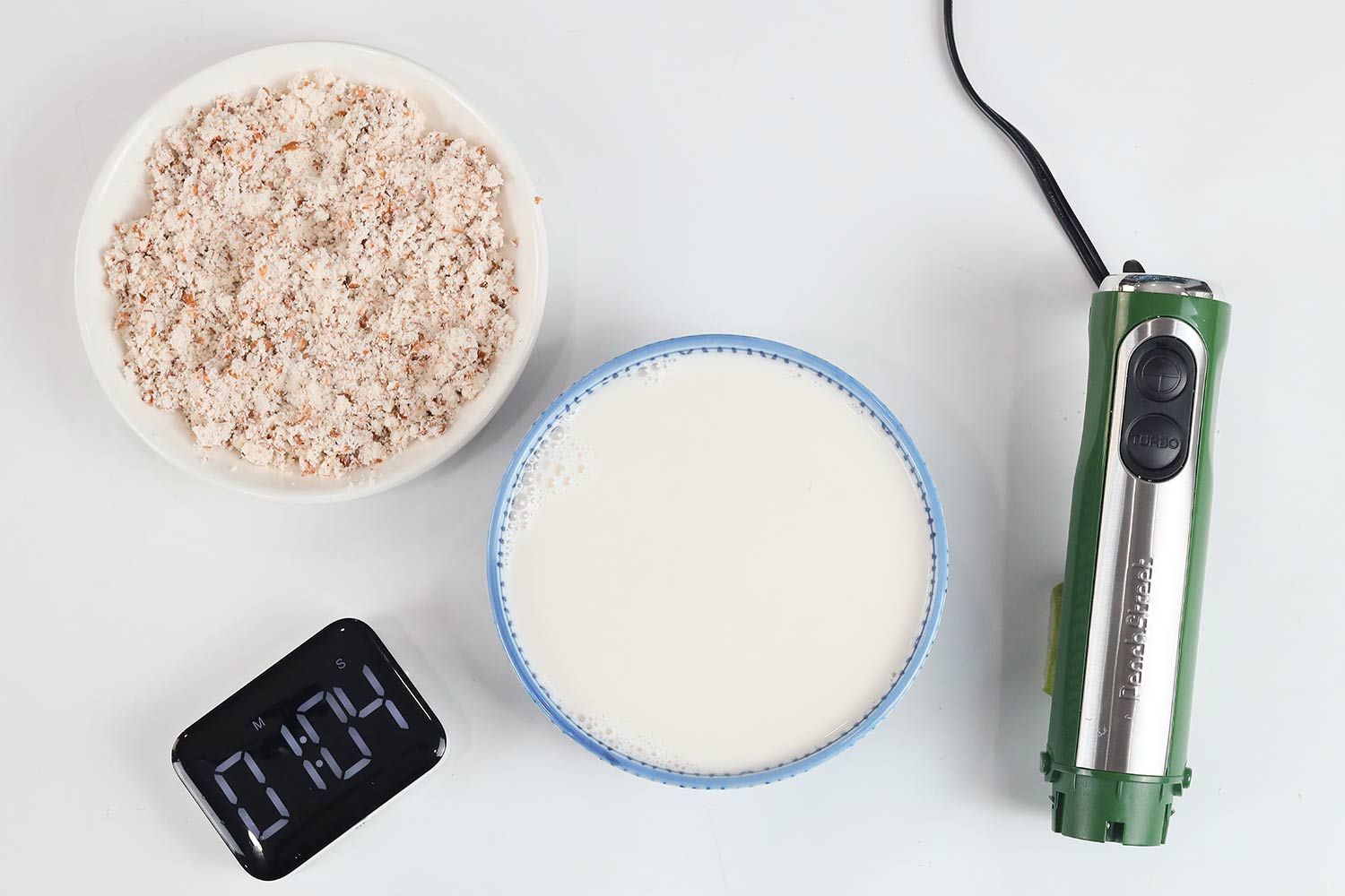 A white plate of almond pulp and a bowl of milk produced by the Peach Street stick blender within 1 minute and 04 seconds.