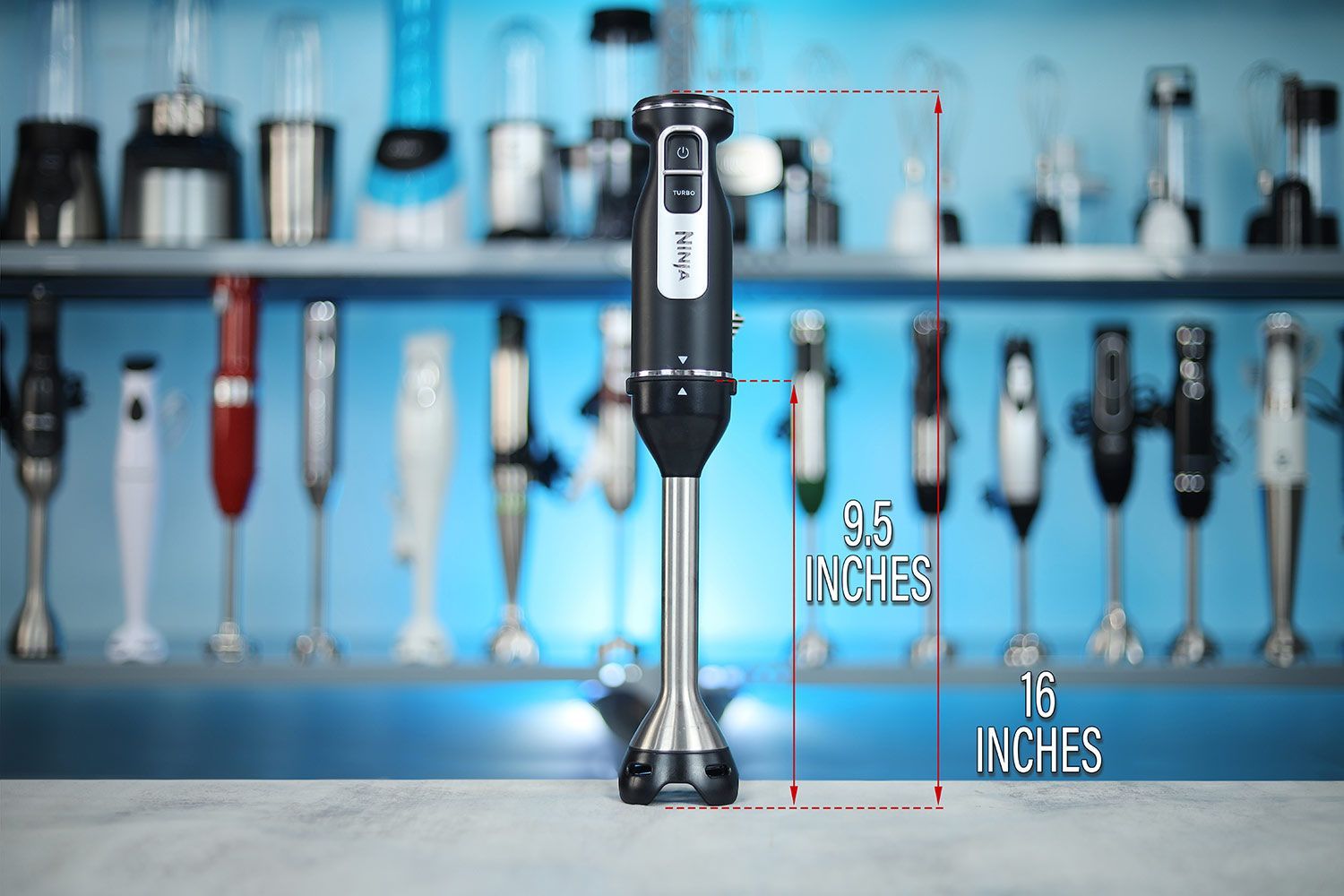 The Ninja Foodi Power Mixer System standing on a table, with the length of its blending shaft being noted to the side as 9.5 inches, and the total length of the unit as 16 inches.  