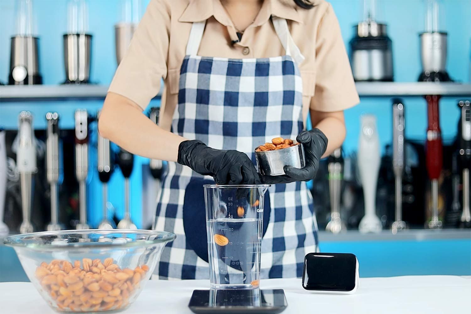 Person adding almonds to beaker containing water