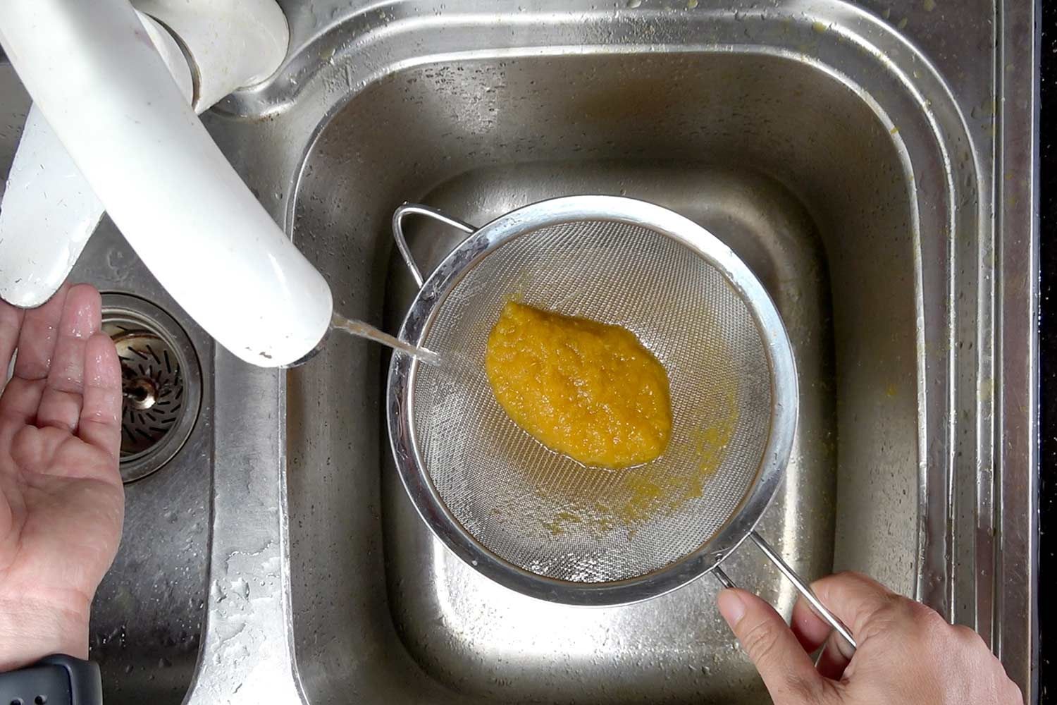 soup being strained under running tap