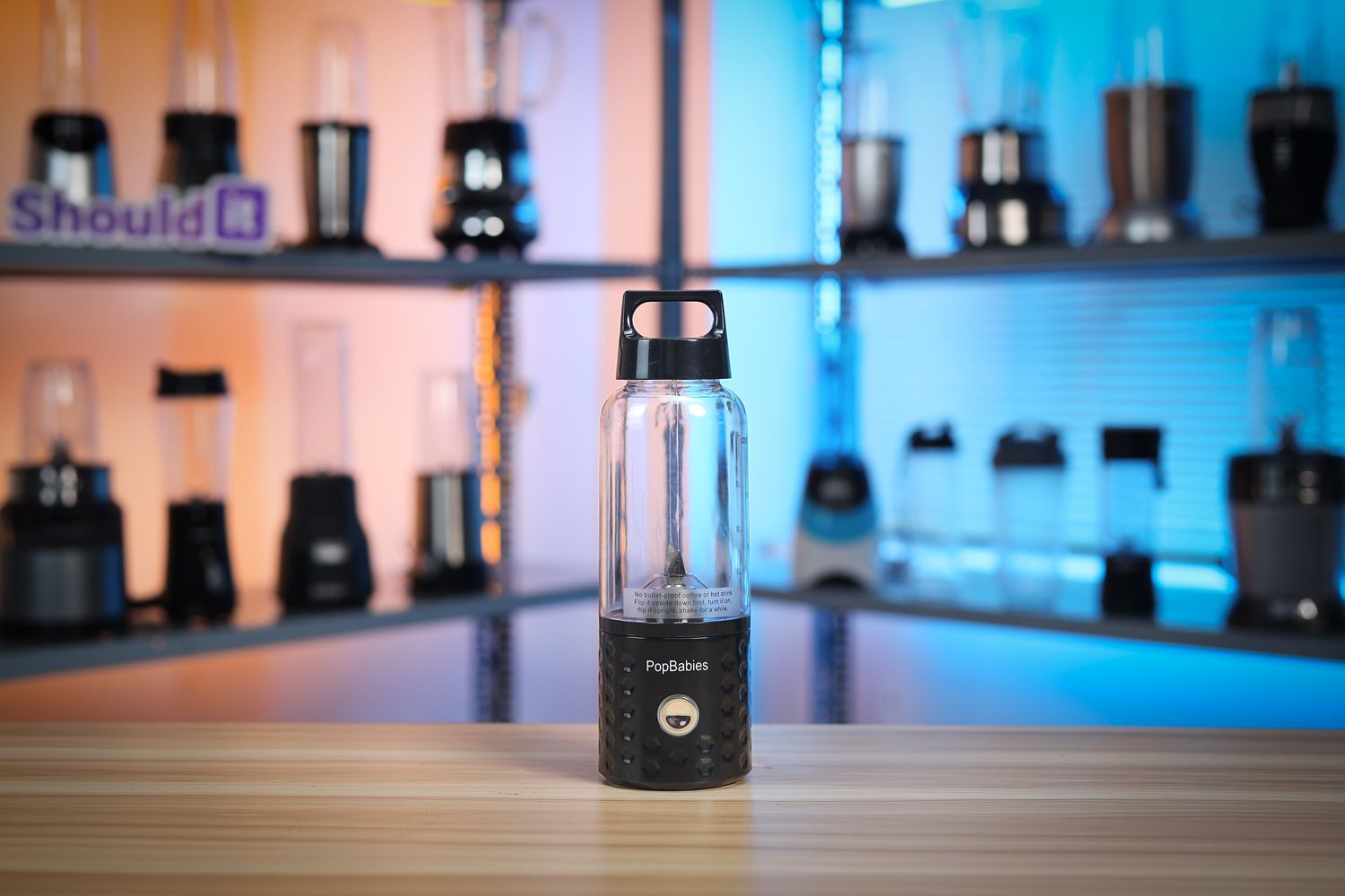 Someone holding the Popbabies cordless portable blender with kitchen appliances in the background.