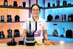 Tina adds frozen mango, pineapple, strawberry, and milk to the Ninja Bl610 full-size blender to evaluate its frozen smoothie performance. She starts blending at the blender’s highest speed while timing the process on her phone. Partway through, she pauses the blender and uses a spoon to stir and loosen the mixture, helping the ingredients circulate and blend more evenly. Once the smoothie is finished, she spreads a small amount onto a sheet to take a closer look at the texture.