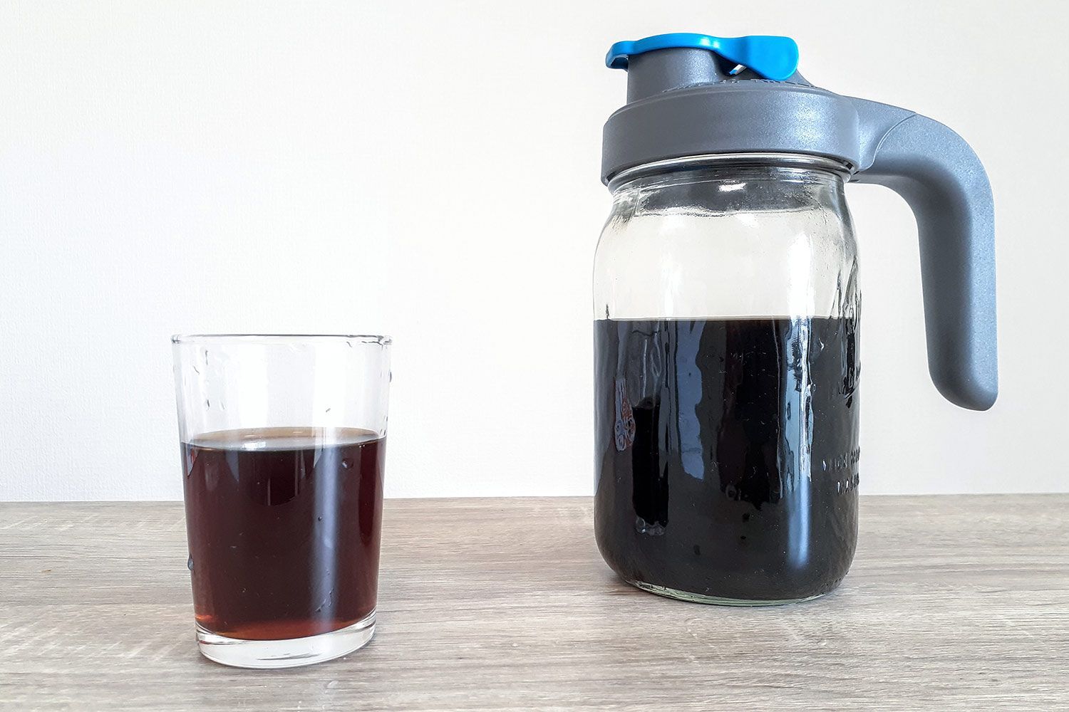 A batch of freshly brewed coffee in the County Line cold brew coffee maker and a glass of coffee to the right.