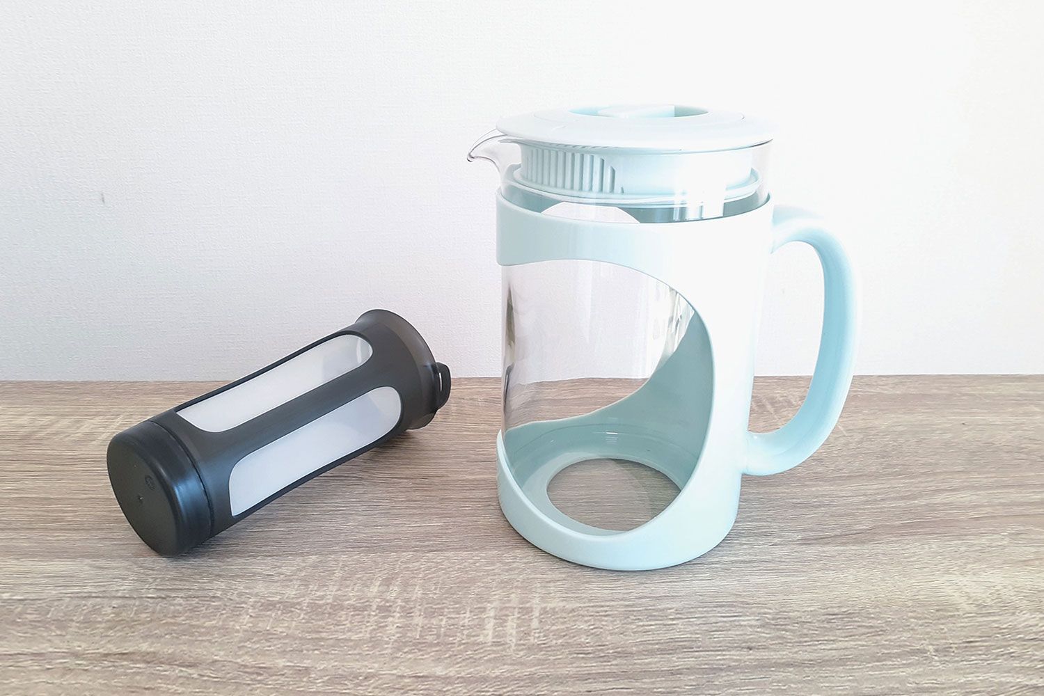 The Primula Burke Deluxe cold coffee maker standing on a counter with its filter picture to the left.