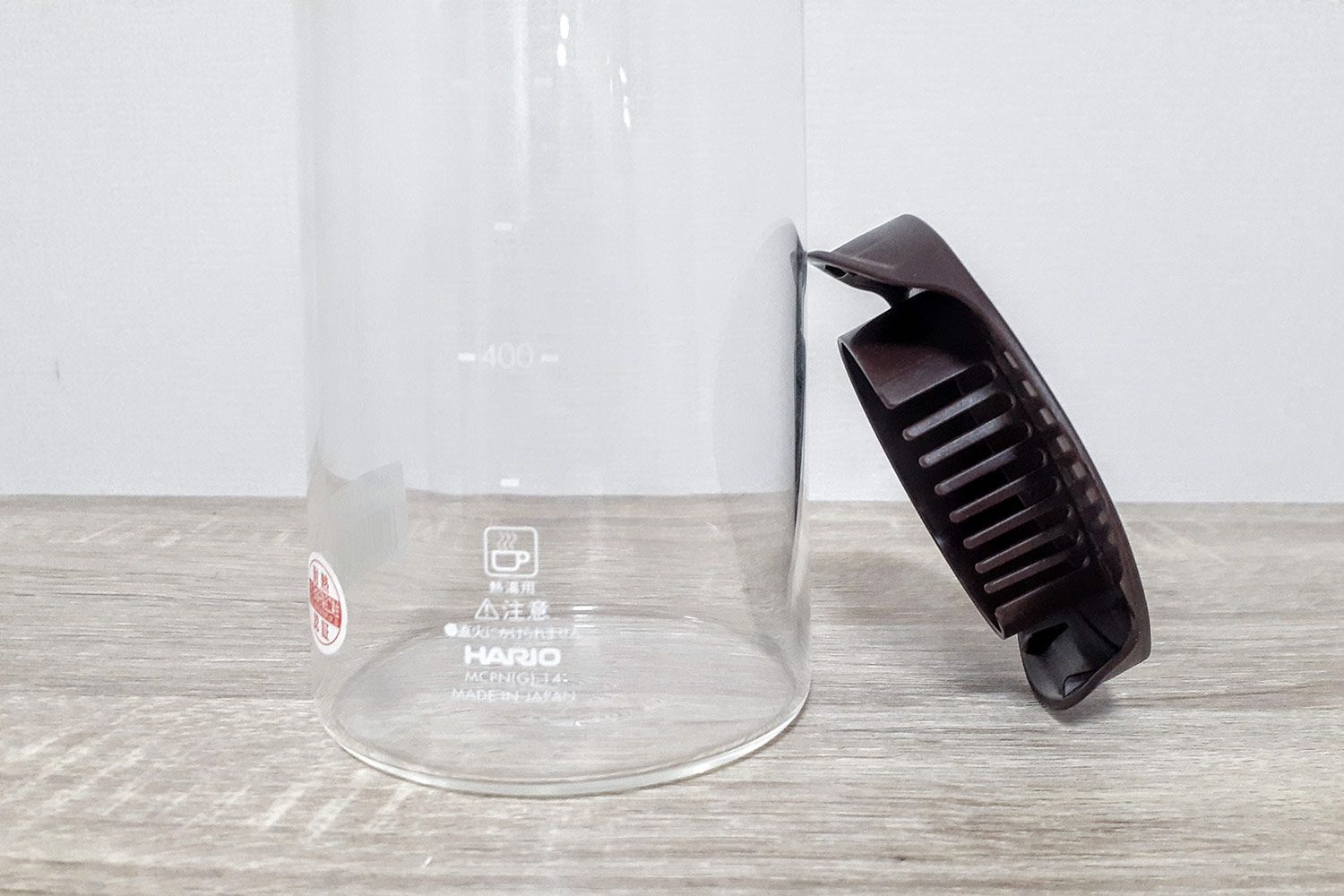 A close up view of a plastic lid standing next to the base of a tall glass carafe.