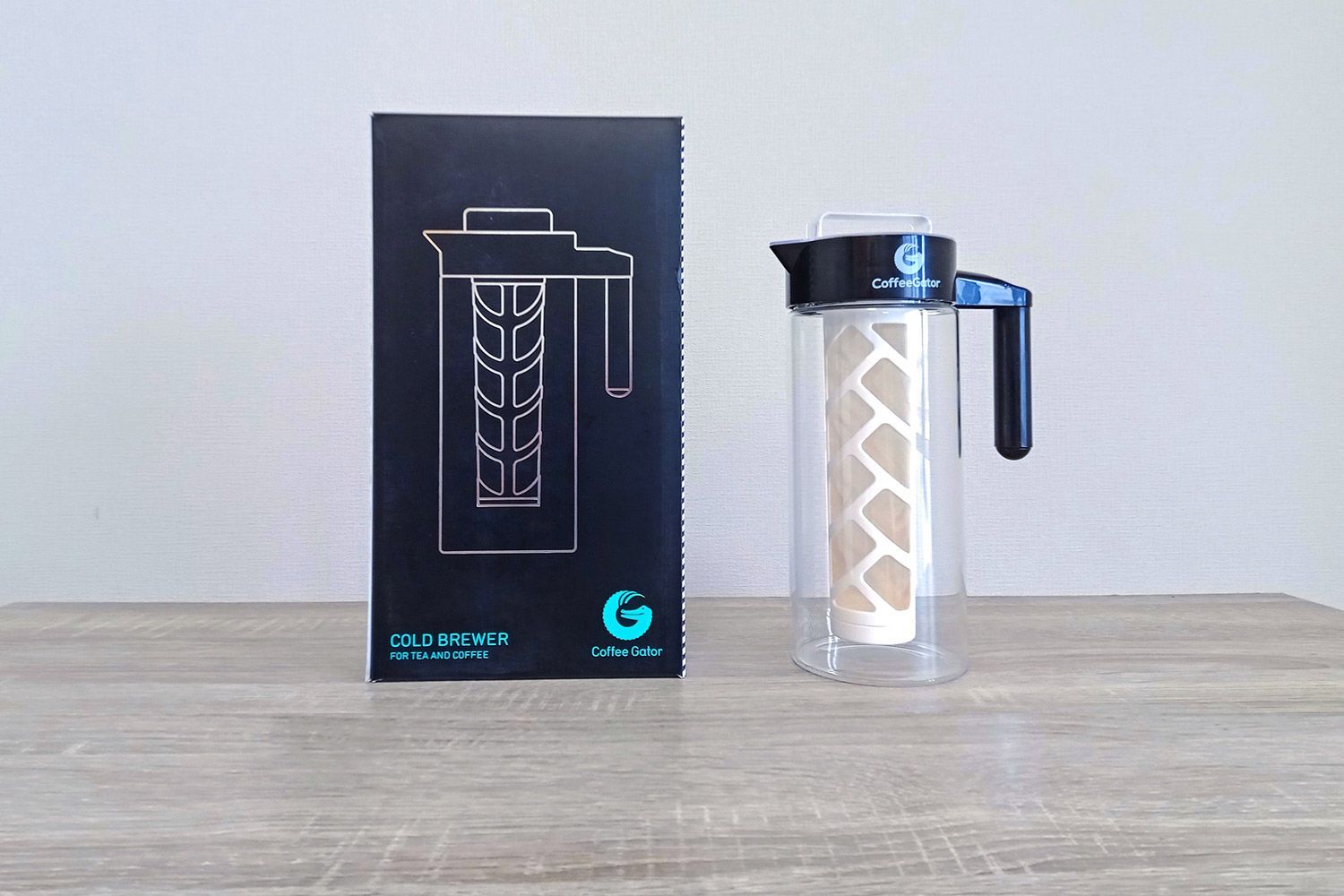 The Coffee Gator cold brew coffee maker standing to the right of its box.