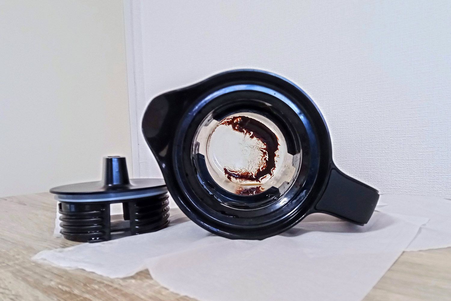 A view inside of a plastic cold brew coffee maker showing remaining sediment after all coffee is carefully decanted.