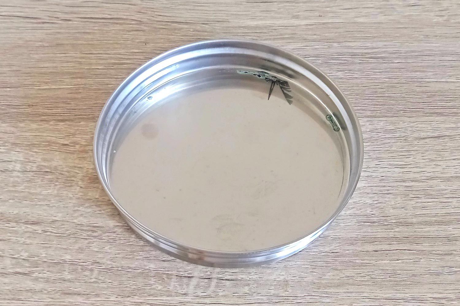 A top down view of the inside of an aluminum lid removed from a mason-jar-type cold brew coffee maker.