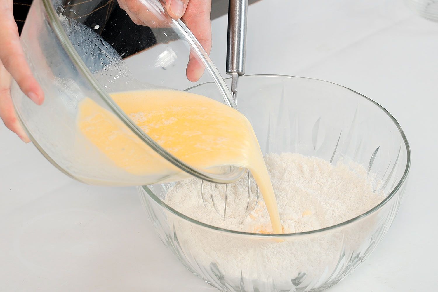 A person pouring the wet ingredients into the dry ingredients.