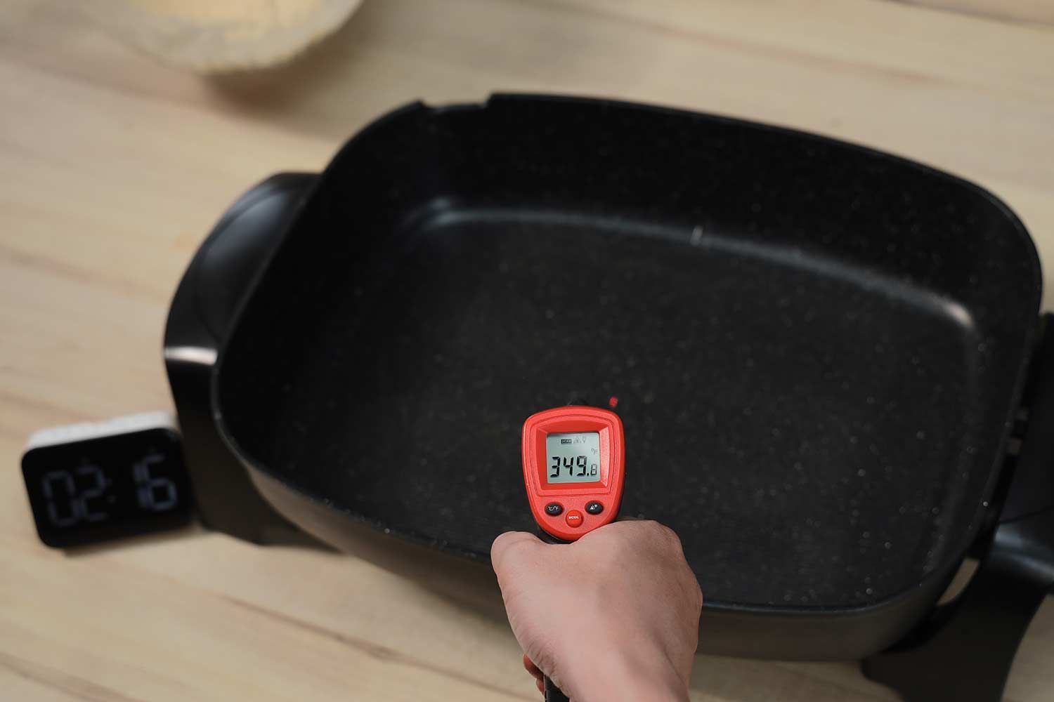 An infrared thermometer reads the temperature on the Elite Gourmet Non-Stick Electric Skillet EG-6203# to be 349°F.