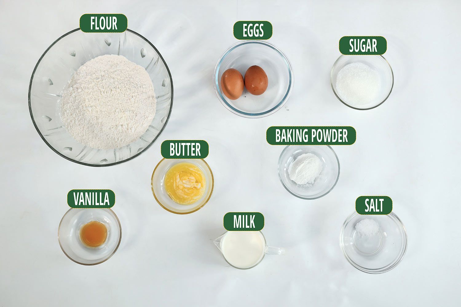 Containers of ingredients including flour, eggs, sugar, baking powder, butter, vanilla extract, milk, and salt.