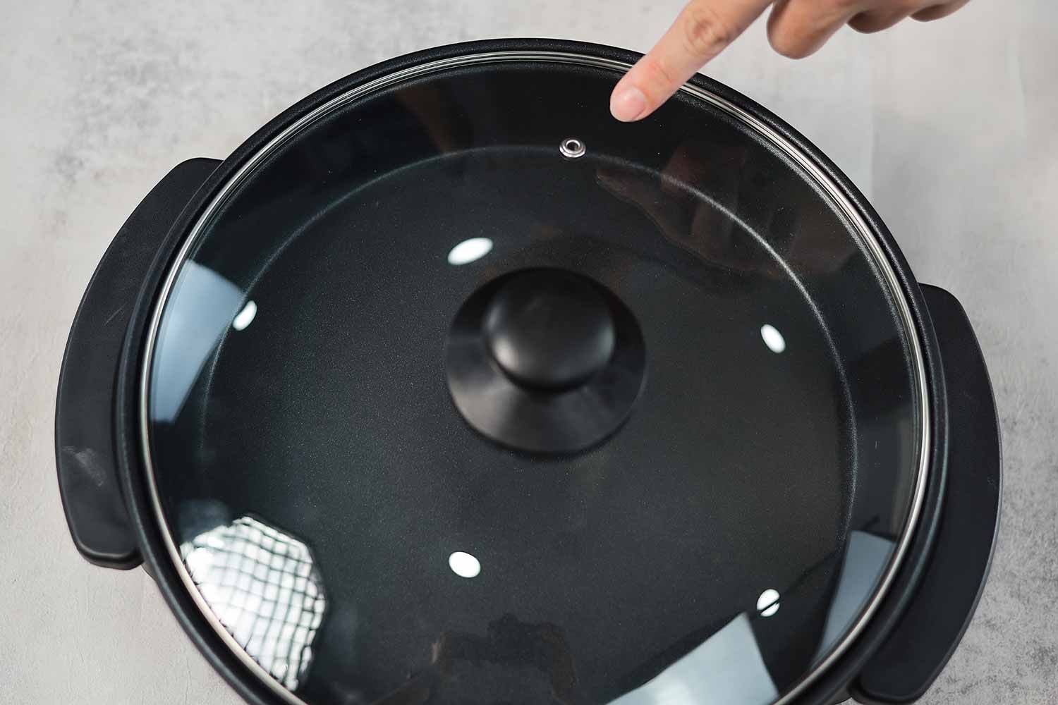 The tempered glass lid of the Ovente Non-Stick Electric Skillet SK11112B has a steam vent.