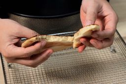 Two hands breaking a pancake apart. In the background is the Ovente Non-Stick Electric Skillet SK11112B.