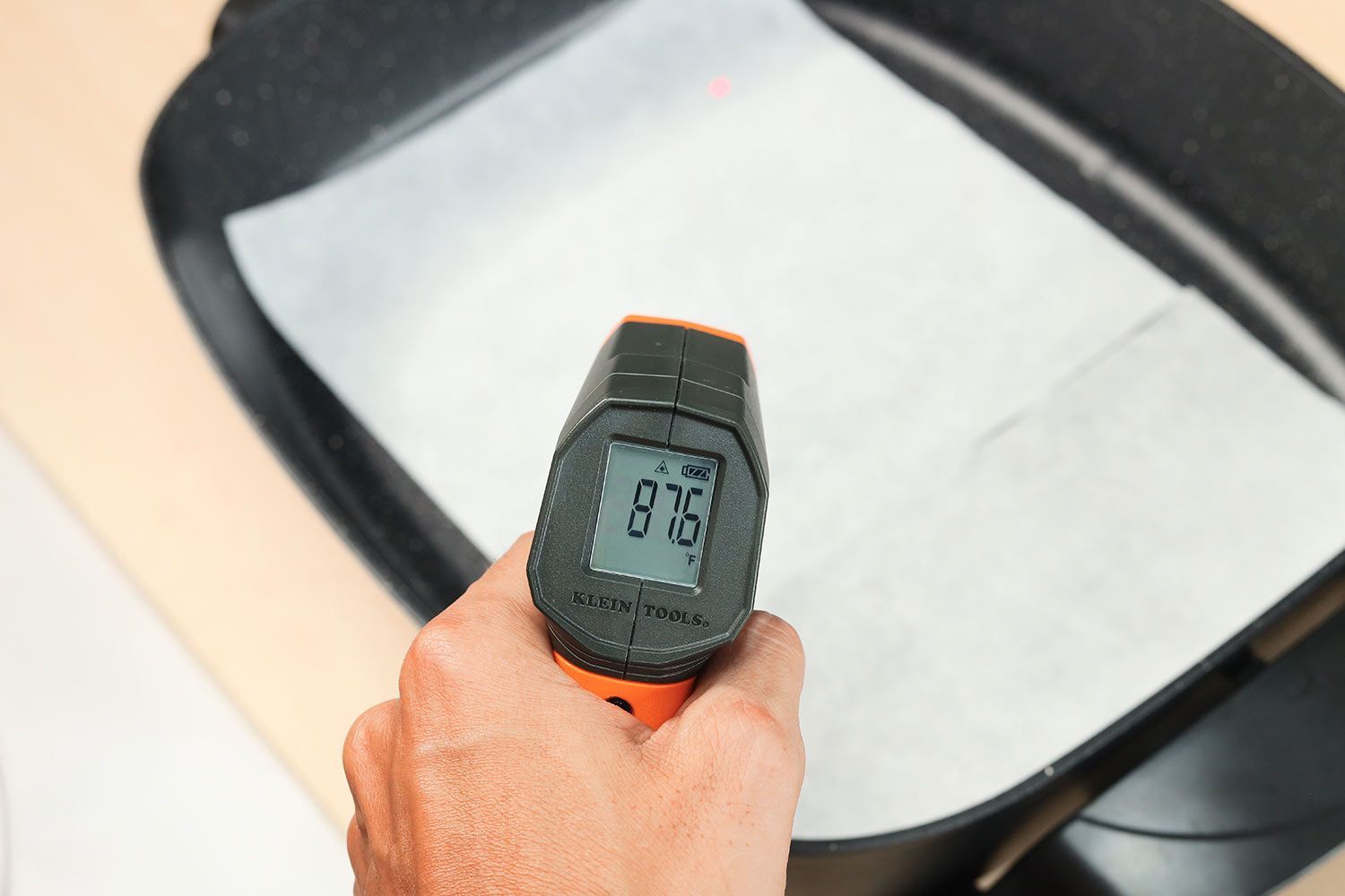 An oil absorbent sheet laid on a skillet’s surface. An infrared thermometer reads 87.6°F.