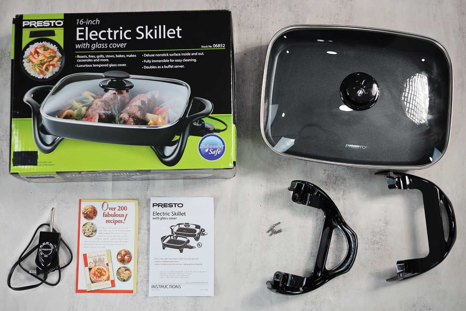 On the upper right is the Presto Electric Skillet 06852. On the left is its cardboard box. Below the skillet from right to left is an instruction manual, a thermostat, and two screw-on handles.