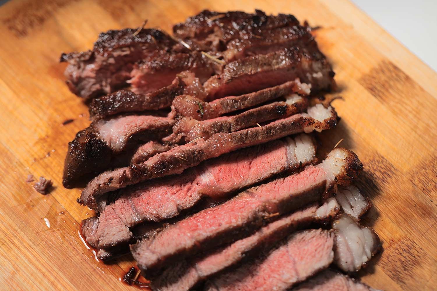 Slices of medium rare steak on a wooden cutting board