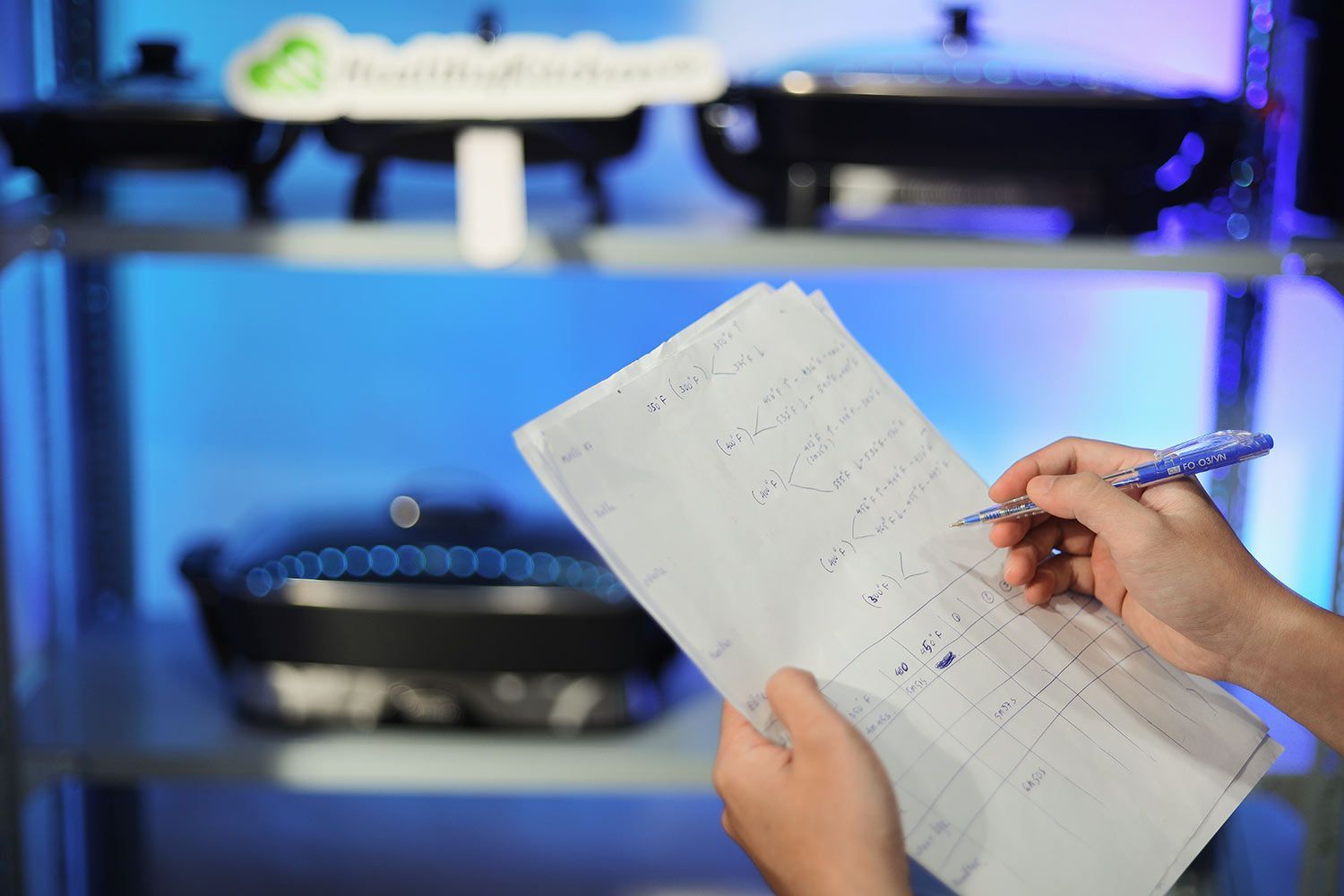 A person holding sheets of paper writing down scores and notes with a pen.