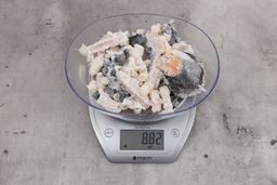 8.82 ounces of ground fish scraps from a garbage disposal, displayed on digital scale, placed on granite-looking table. Mess of shredded fish backbone and skin.