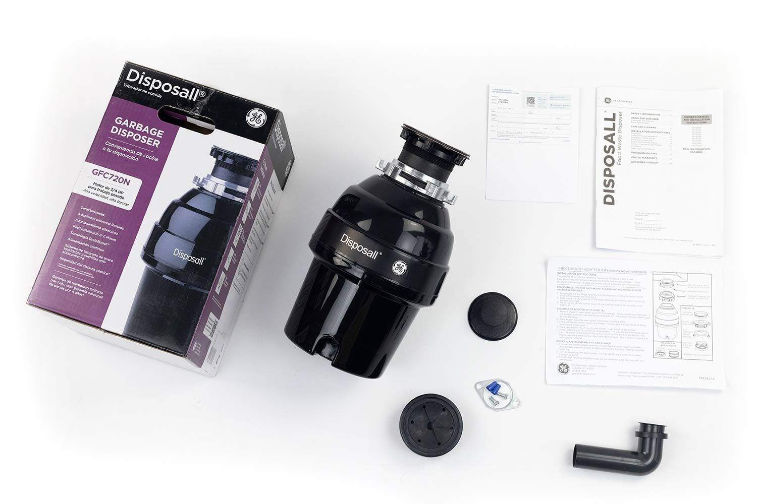 GE Disposall GFC720N 3/4 HP with EZ Mount assembly on top, next to its box, registration slip, user manual, installation instruction, sink stopper, adapter kit, elbow tube with rubber gasket, flange, bolts, and wire nuts.