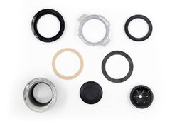 Parts of EZ Mount assembly for garbage disposals displayed on white platform, including support ring, mounting ring, cushion mount, fiber gasket, rubber gasket, sink flange with “GE Disposall” engraving, stopper, removable sink baffle/splash guard.