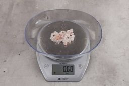 0.68 ounces of ground chicken scraps from garbage disposal, displayed on digital scale, placed on granite-looking table. Mess of soft tissue and pieces of shredded cartilage.