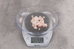 1.12 ounces of ground chicken scraps from garbage disposal, displayed on digital scale, placed on granite-looking table. Mess of shredded soft tissue and bones.