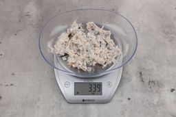 3.39 ounces of ground fish scraps from garbage disposal, displayed on digital scale, placed on a granite-looking table. Mess of assorted shredded bones and fibrous tissue.