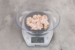 2.25 ounces of ground chicken scraps from garbage disposal, displayed on digital scale, placed on granite-looking table. Mess of shredded tendons and shredded bones.