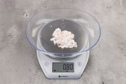 0.8 ounces of ground chicken scraps from garbage disposal, displayed on digital scale, placed on granite-looking table. Mess of shredded soft tissues and shredded bones.