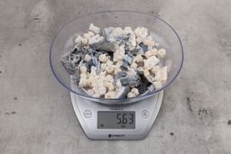 5.63 ounces of broken fish vertebrae and shredded fish skin on digital scale on granite-looking top.