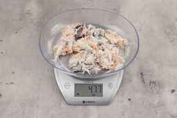 4.77 ounces of visible pin bones in a mass of raw meat and skin from fish scraps on digital scale on granite-looking top.