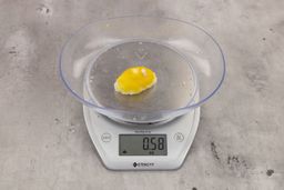 0.58-ounce piece of lemon peel from garbage disposal on digital scale on granite-looking table